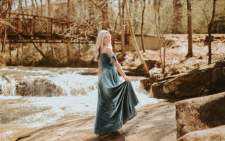 A young lady is standing in the forest, wearing AW velvet bridesmaid dress.