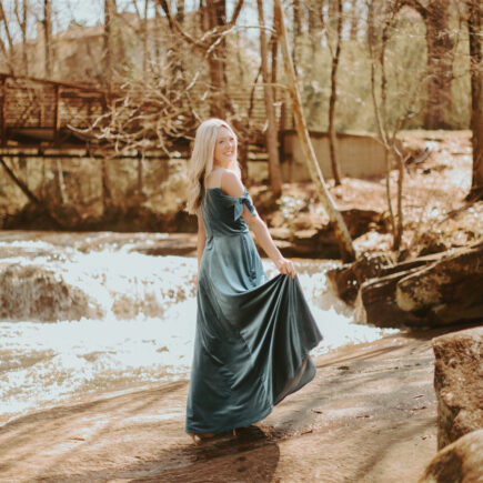 A young lady is standing in the forest, wearing AW velvet bridesmaid dress.