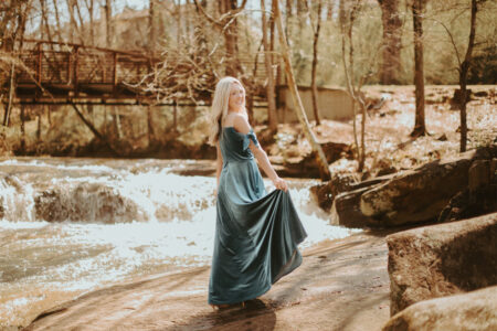 A young lady is standing in the forest, wearing AW velvet bridesmaid dress.