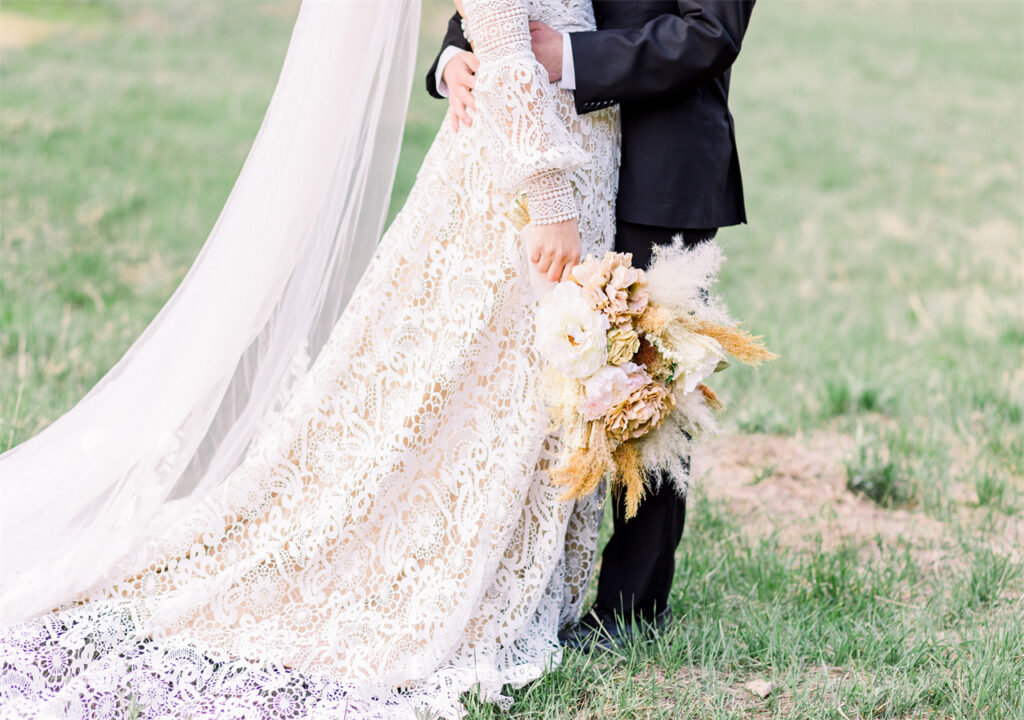 A bride is kissing her husband, holding a bunch flower in her hands.