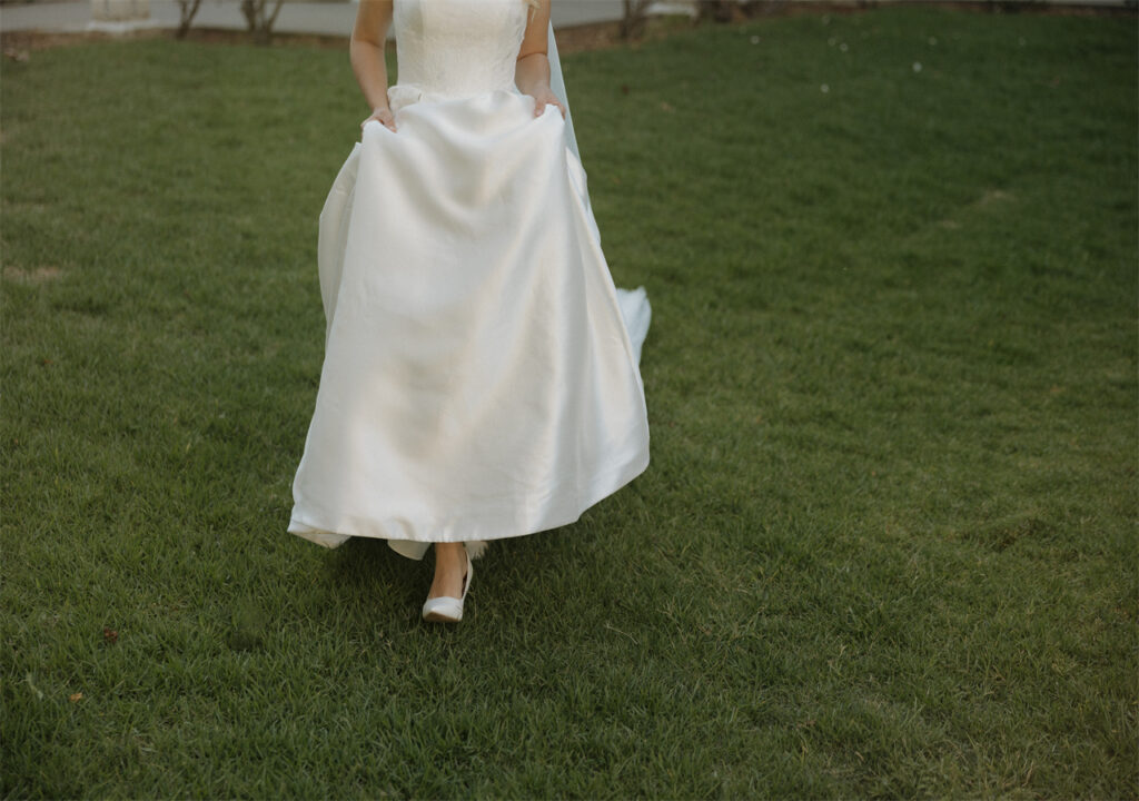 A bride trotted happily on the grass holding her skirt, preparing to attend the wedding.