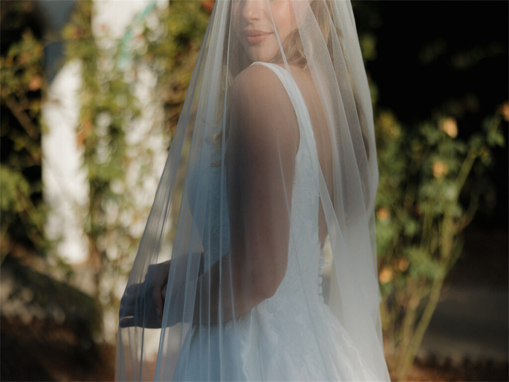 Under the summer sun, a blonde bride smiles for the camera.