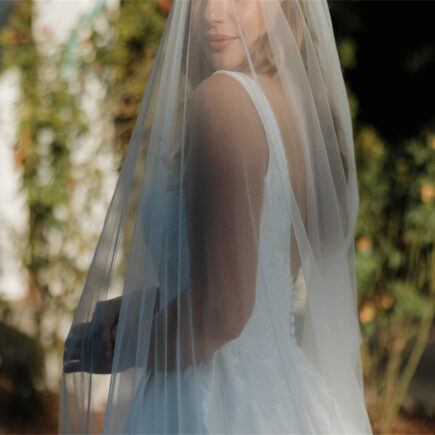 Under the summer sun, a blonde bride smiles for the camera.