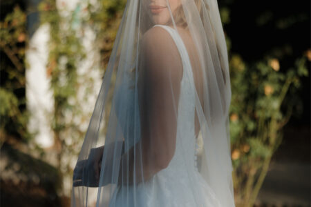 Under the summer sun, a blonde bride smiles for the camera.