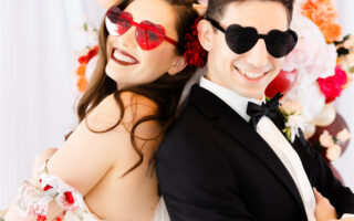 A couple are wearing colored glasses and laughing