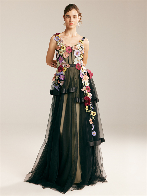 Model in a black gown with colorful floral appliques.