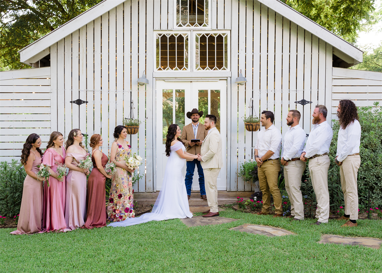 Bride and groom holding hands at their wedding with witnesses around them.