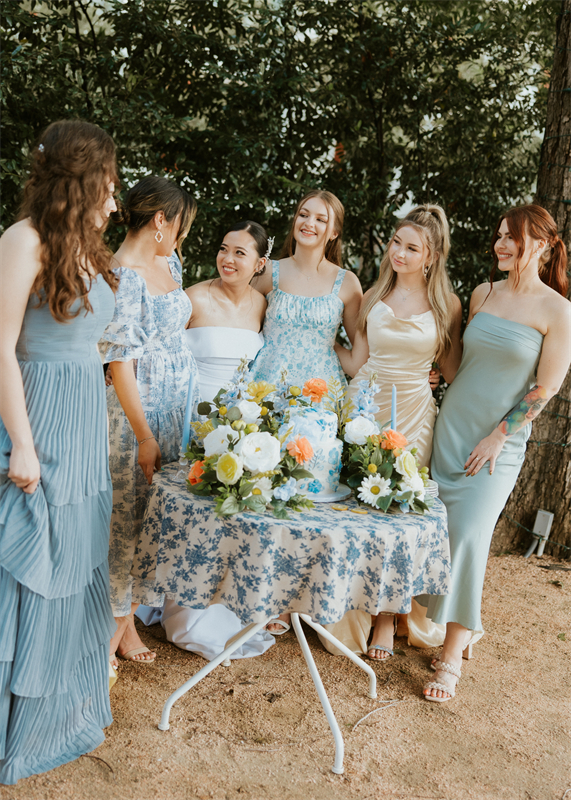 A bride and her wedding guests standing around a table, smiling and chatting.