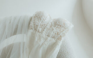 Close-up of a lace wedding dress draped over a textured chair.