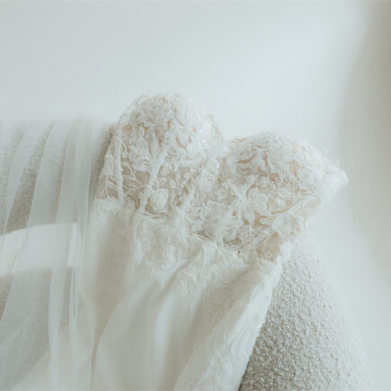 Close-up of a lace wedding dress draped over a textured chair.