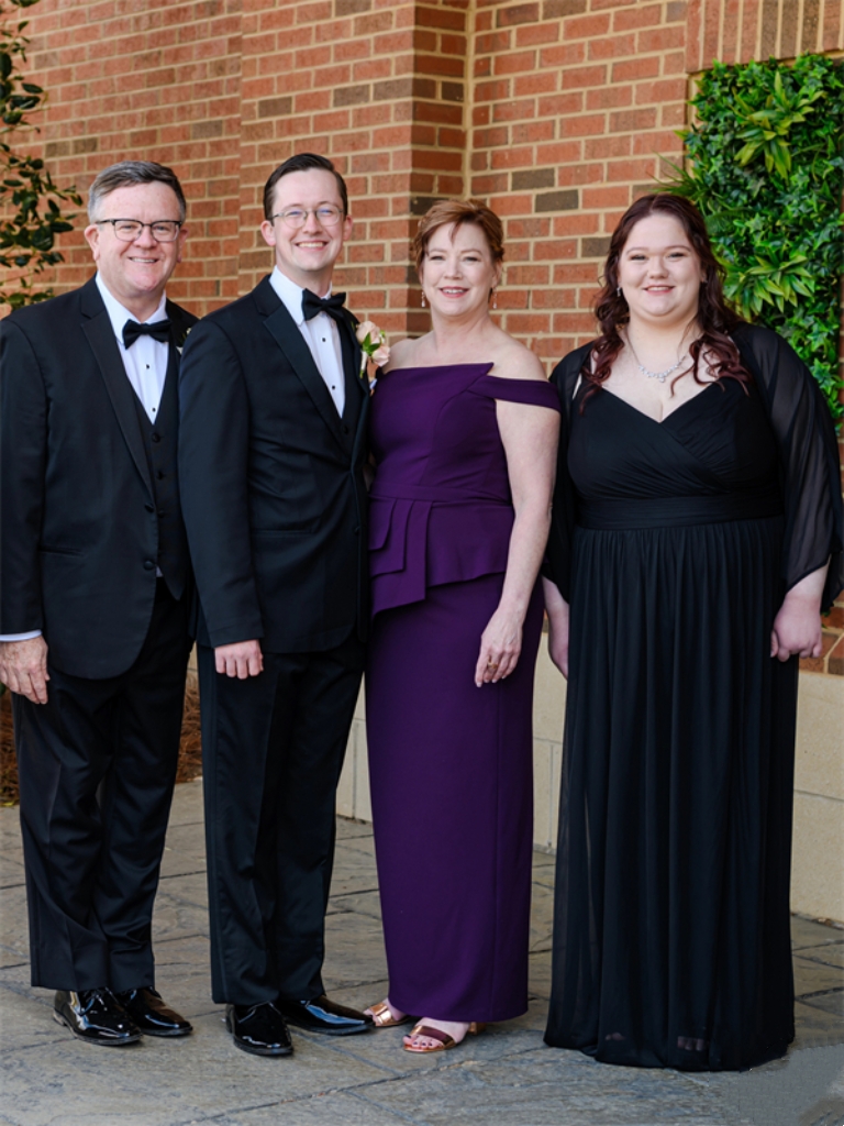 Wedding guests smiling for a portrait in front of a brick wall.