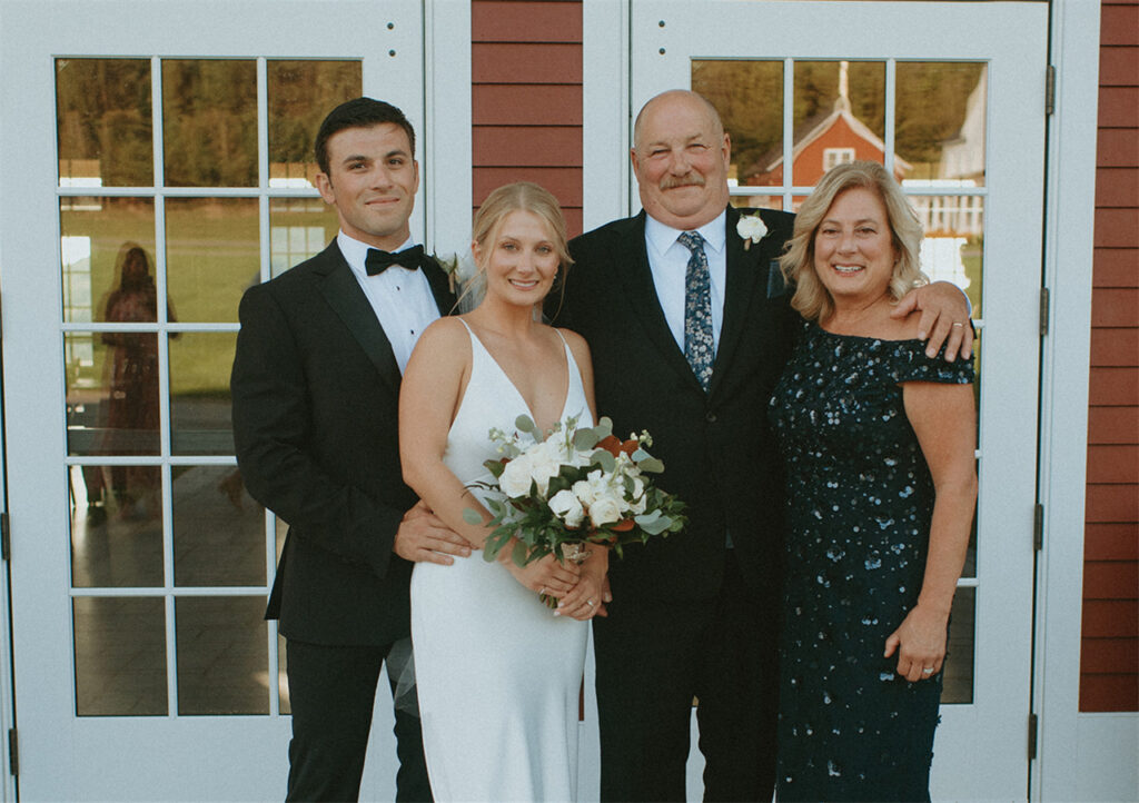 A couple posing with parents in front of a building.