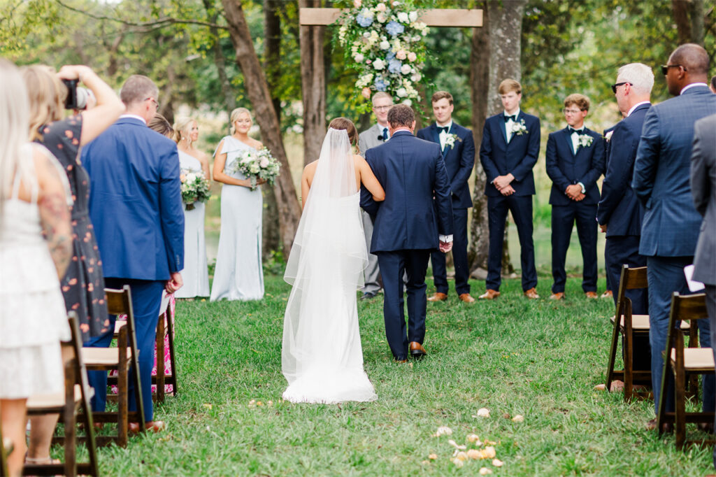 A bride walks down the aisle at an outdoor wedding.