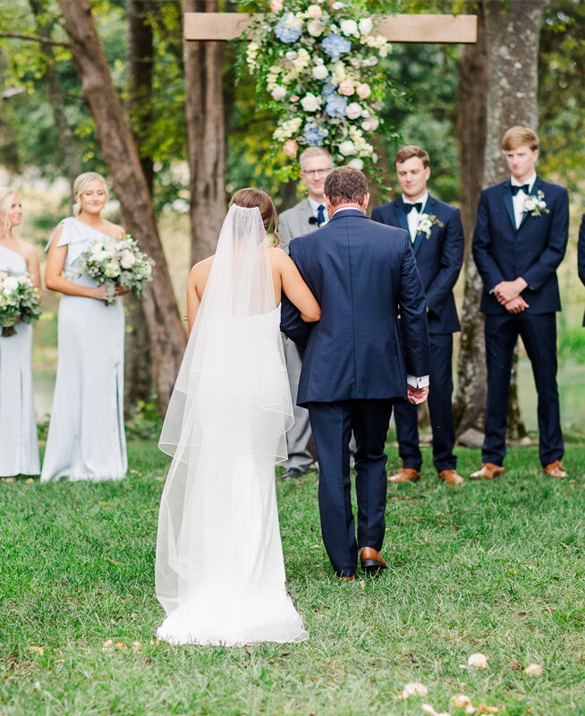 A bride walks down the aisle at an outdoor wedding.